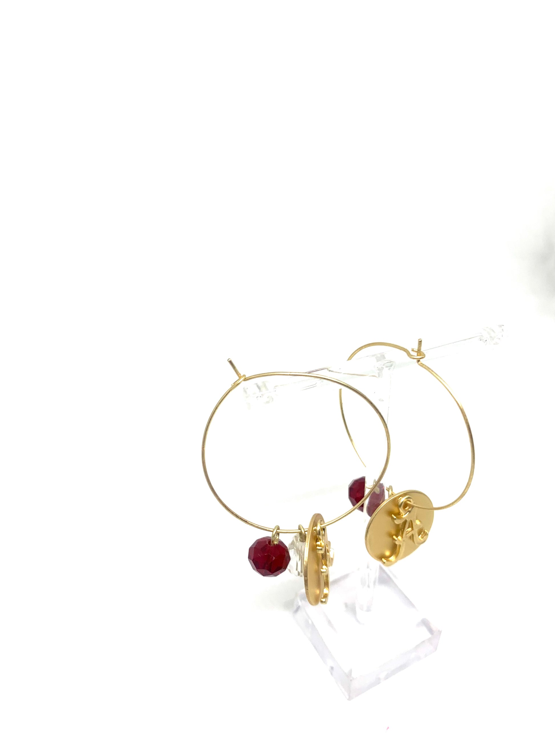 Roll with the Tide in these University of Alabama gold hoops. Show your support for Alabama while being simple and stylish. These gold kidney wire closure hoops feature the University of Alabama logo on a circle charm and maroon bead, Perfect for all your game day looks. 